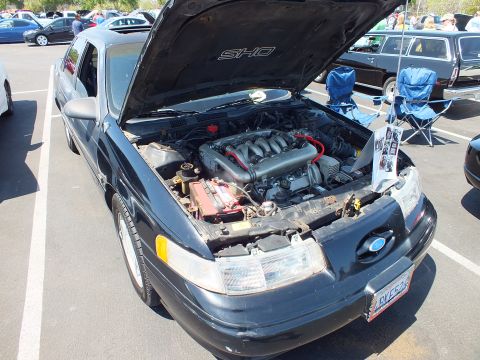Black Ford Taurus SHO sedan with hood open showing V6, SHO label underside