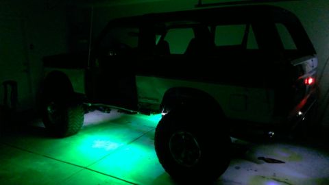 1994 Ford Bronco - A 1994 Ford Bronco is shown with vibrant green underglow lighting illuminating the garage floor.