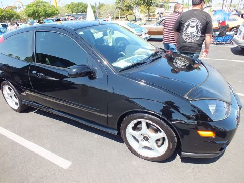 Black Ford Focus three-door hatchback with white wheels at car show