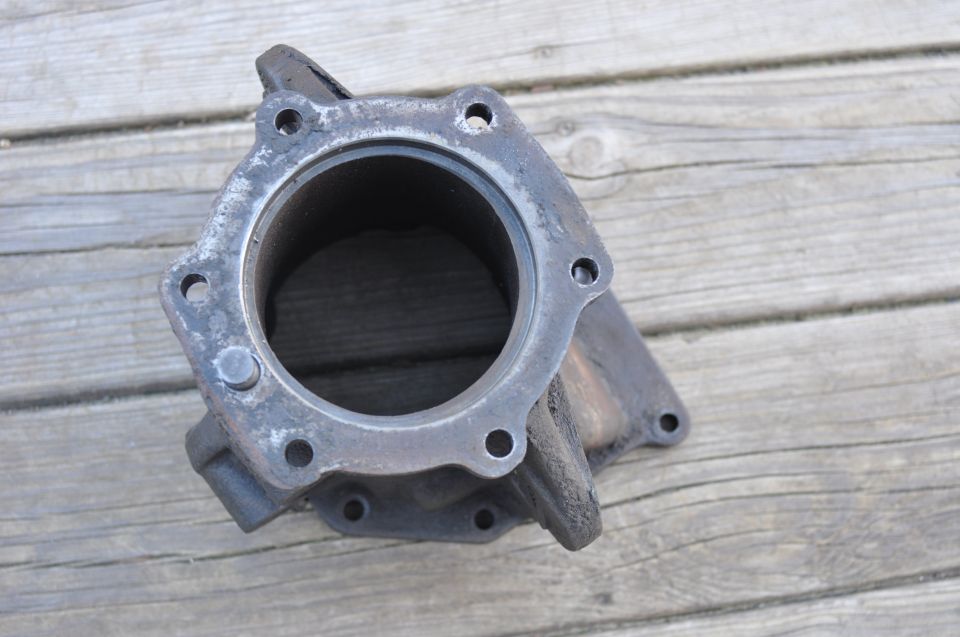 Cast iron engine part with bolt holes on a wooden surface