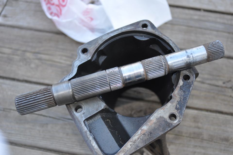 Driveshaft resting inside a metal housing, likely part of a transmission or transfer case