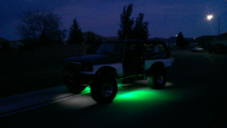 Lifted Ford Bronco with green underglow lights at night