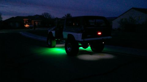 1994 Ford Bronco - This modified SUV, likely from the 1980s, is viewed from the rear with vibrant green underglow lighting illuminating the ground.