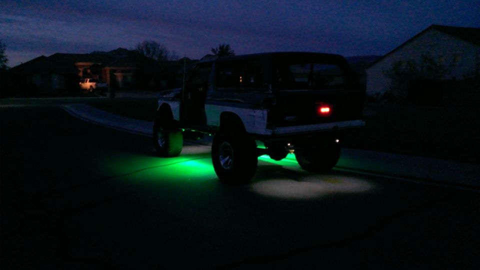 Lifted SUV with green underglow lights, rear view, dark exterior, aftermarket wheels