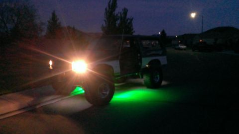 1994 Ford Bronco - A black SUV with bright green underglow lights illuminates the street at dusk.