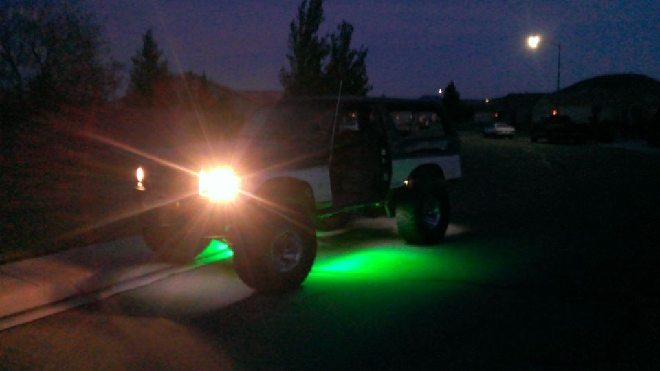 Black SUV with green underglow lights at night