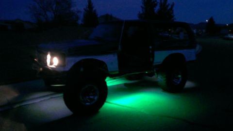 1994 Ford Bronco - 1994 Ford Bronco parked at night with green underglow lighting visible.