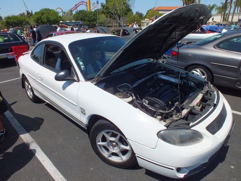 White Ford Escort ZX2 coupe with hood open at sunny car show