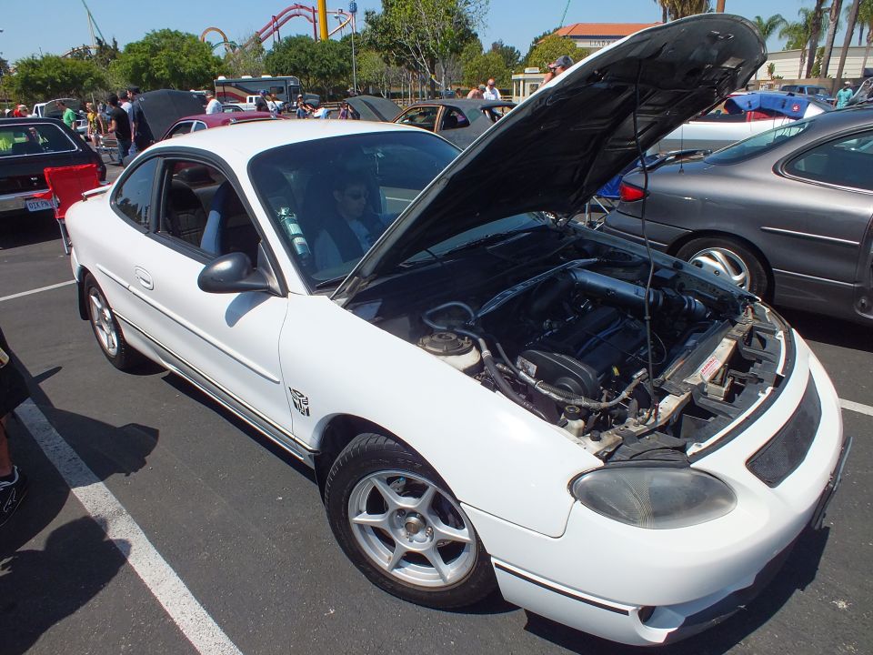 White Ford Escort ZX2 coupe with hood open at sunny car show