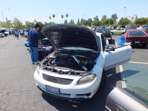 White Ford Escort ZX2 coupe with hood and door open at car show