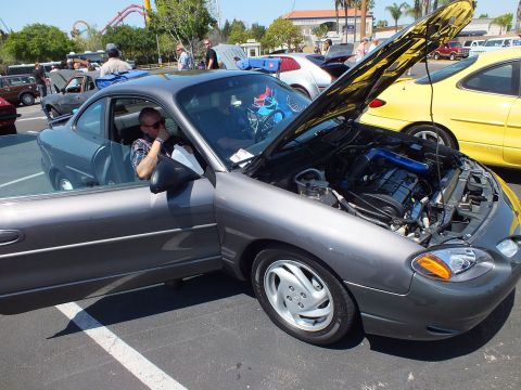 Gray Ford Escort ZX2 coupe with hood open and driver seated
