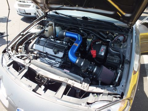 Engine bay with blue intake piping and cone air filter in coupe