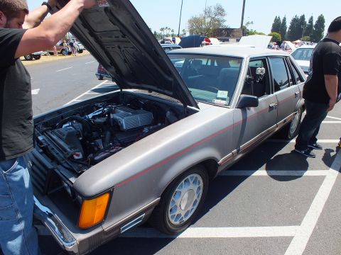Silver Ford four-door sedan with hood open at car show