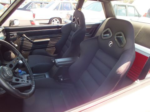 Car interior with black aftermarket racing-style bucket seats and red trim