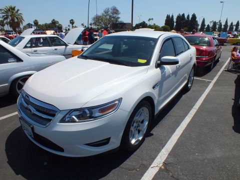 Front three-quarter of a white Ford Taurus sedan at an outdoor car show