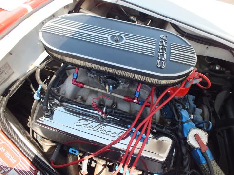 V8 engine with finned COBRA valve cover and Edelbrock intake, red plug wires
