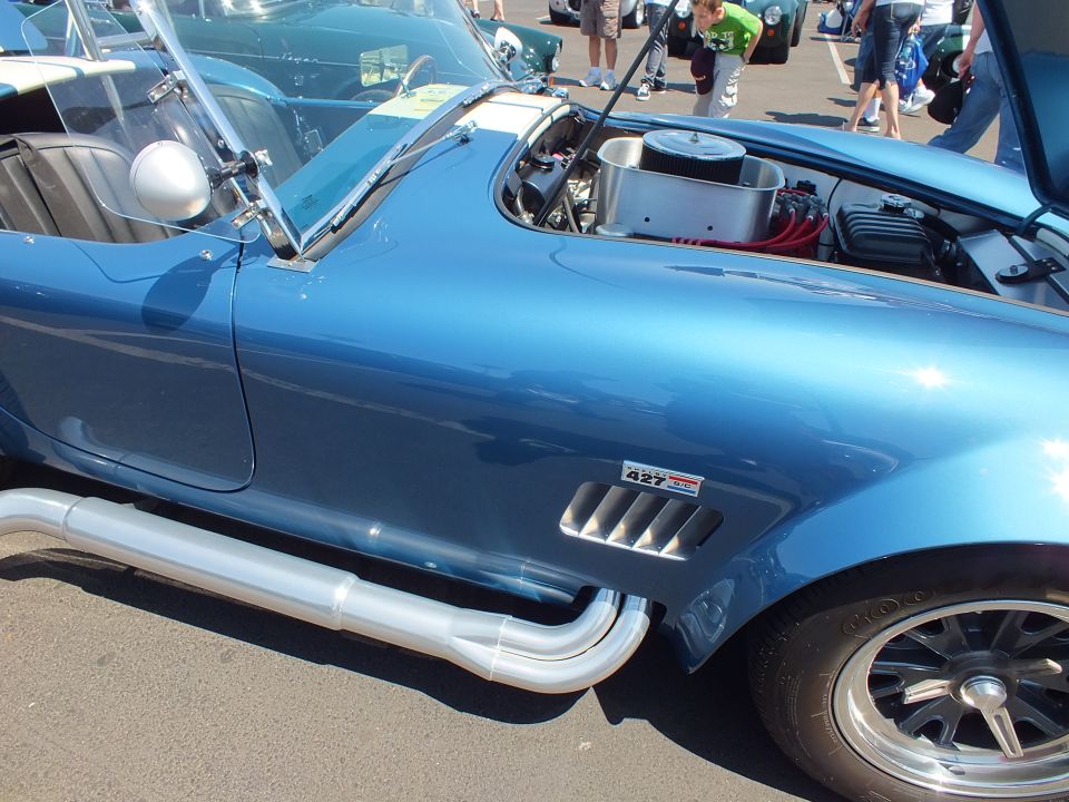 Side view of a blue-grey Cobra-style roadster with 427 fender badge and chrome side pipe