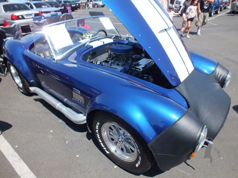 Blue Cobra-style roadster with black fender flares, hood up, Sidehawk tires