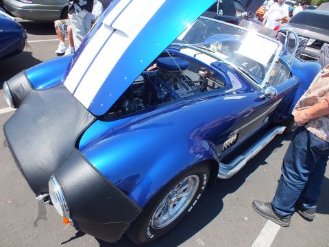 Blue Cobra-style roadster with black flares, hood open showing chrome air cleaner