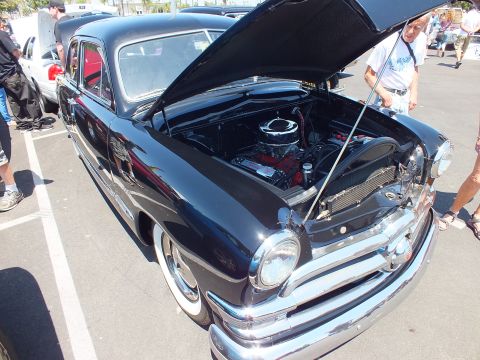 Black vintage Ford sedan with open hood at an outdoor show