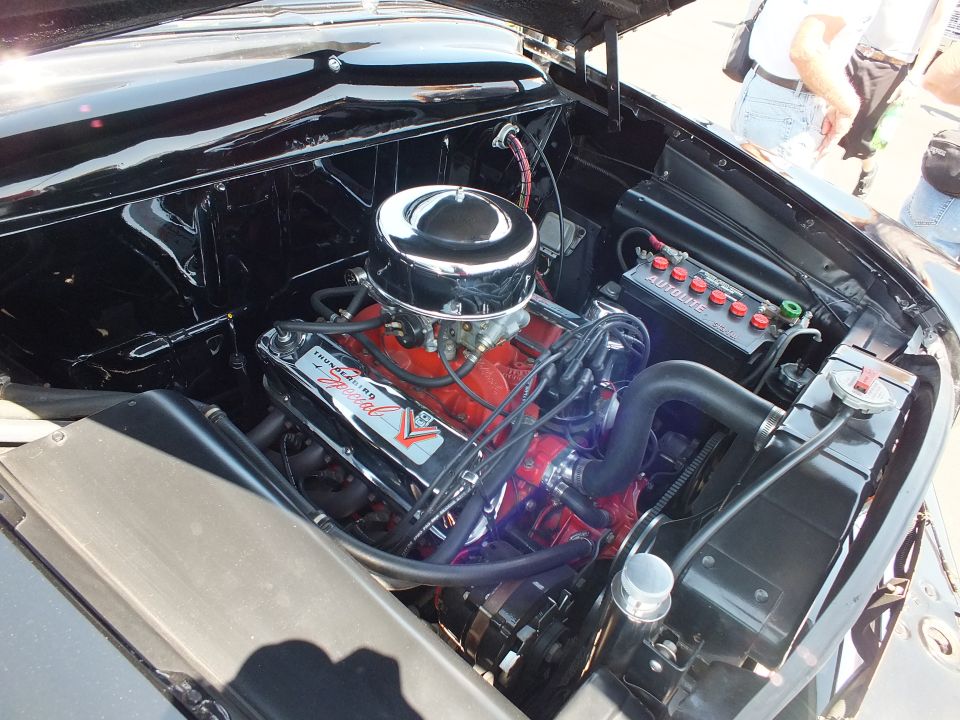 Engine bay of a classic car with a red V8 and chrome air cleaner