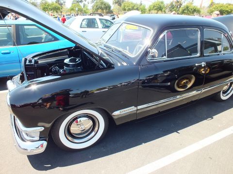 Side view of a black vintage Ford sedan with whitewall tires