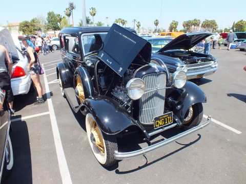 Black 1932 Ford hot rod with gold wire wheels and open hood