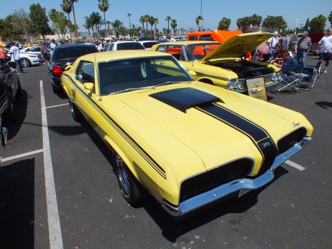 Yellow Mercury Cougar with black stripes and open hood at a show