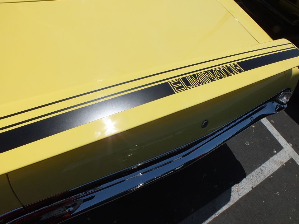 Close-up of a yellow car's deck lid with ELIMINATOR stripe graphic