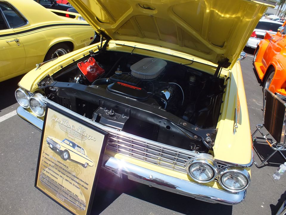 Engine bay of a yellow classic car with open hood and chrome air cleaner