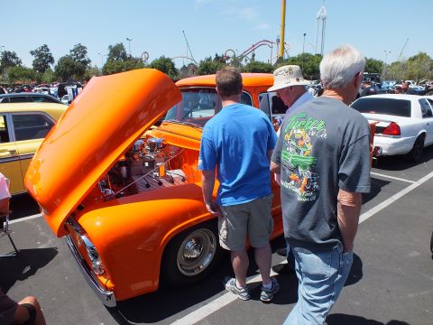 Orange custom pickup with open hood and people gathered around it