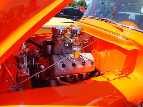 Polished V8 engine with dual carburetors in an orange custom vehicle