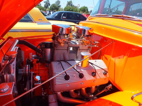 V8 engine with twin chrome air cleaners in an orange hot rod engine bay