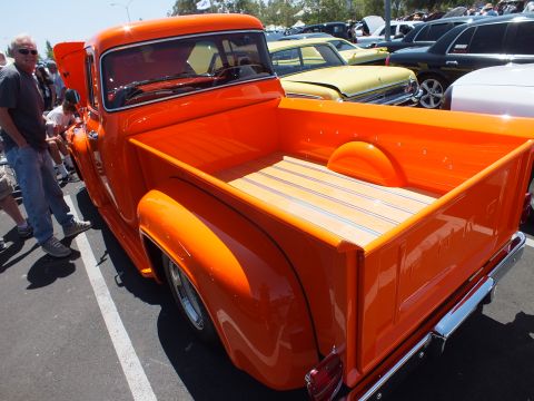 Rear bed of an orange custom pickup truck with wood-slat floor