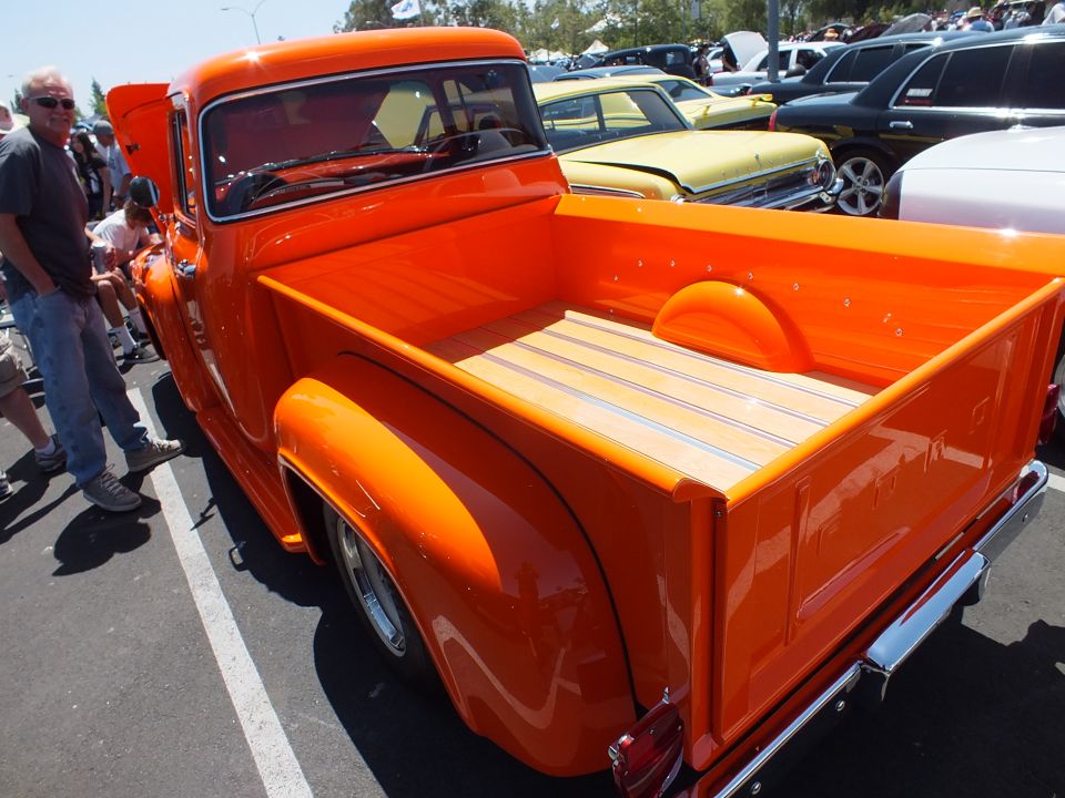 Rear bed of an orange custom pickup truck with wood-slat floor