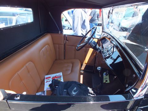 Tan leather interior with steering wheel of a black vintage roadster