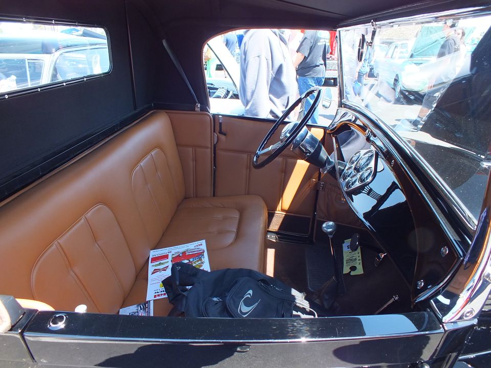 Tan leather interior with steering wheel of a black vintage roadster
