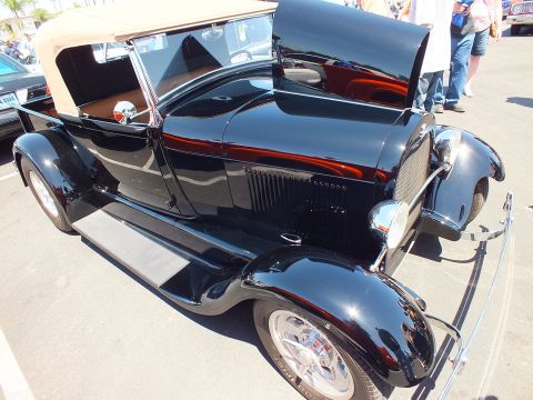 Black vintage hot rod roadster pickup with tan top at a car show