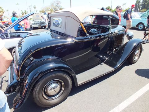 Black 1930s roadster with folding tan top, side view at a car show