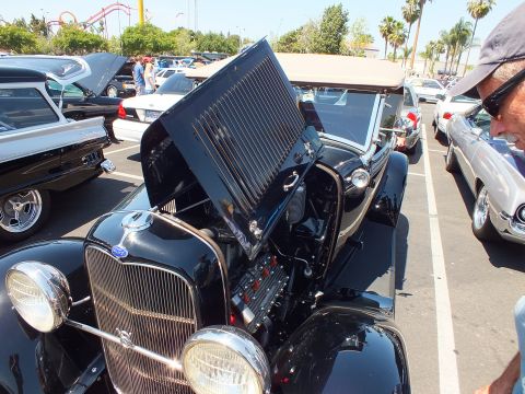 Black Ford roadster with open hood at an outdoor car show