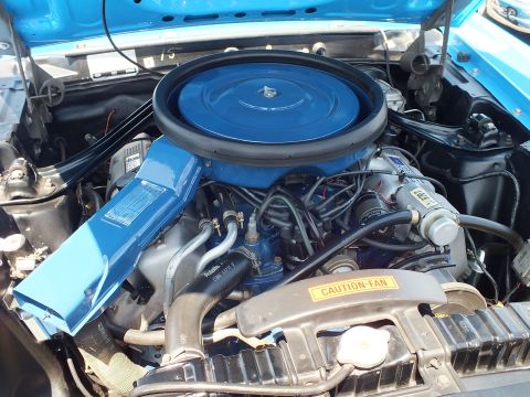Close-up of a blue Ford V8 with round air cleaner and caution-fan decal