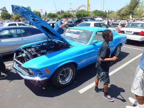 Light blue Ford Mustang coupe with open hood, boy walking past