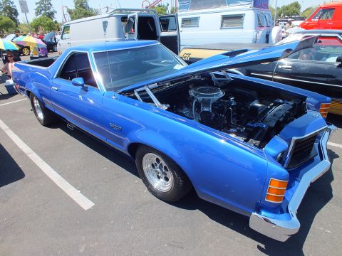 Blue Ford Ranchero coupe-utility with raised hood and chrome wheels at a show
