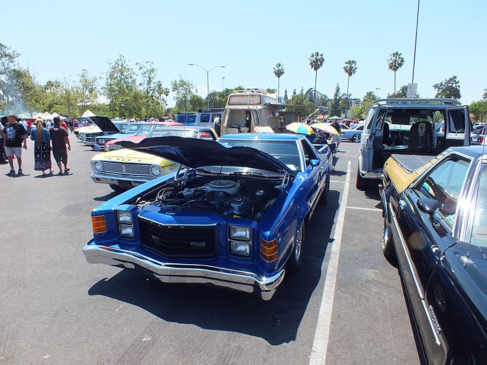 Front view of a blue 1970s coupe-utility with open hood showing engine at a car show