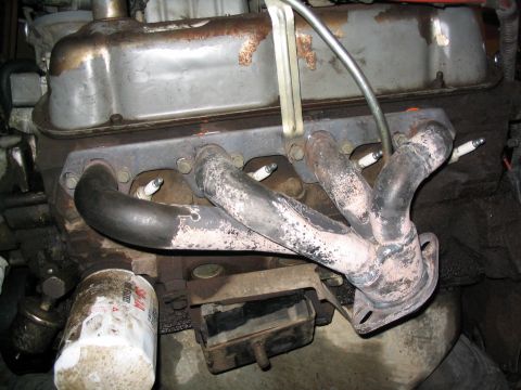 1988 Ford Bronco - Close-up of an engine's exhaust manifold and spark plugs, with an oil filter present.