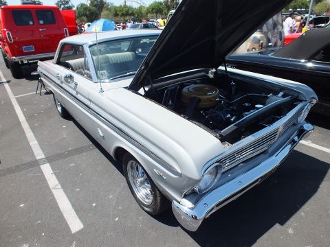 Silver-gray mid-1960s Ford Falcon hardtop with open hood at a car show