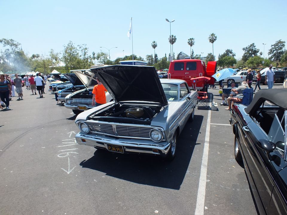 Silver 1965 Ford Falcon with open hood, front view in a crowded car-show lot
