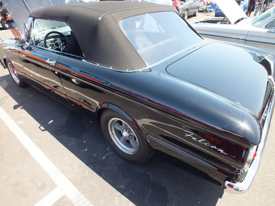 Rear three-quarter of a black Ford Falcon convertible with orange-blue side stripes