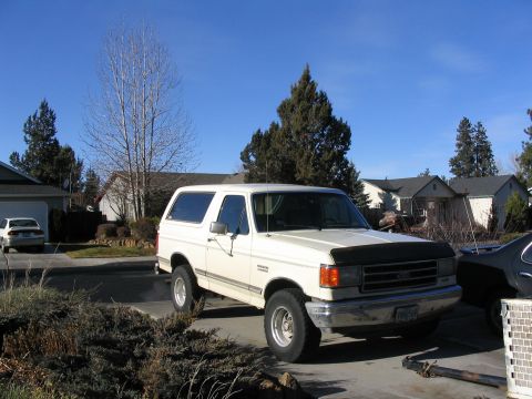 1988 Ford Bronco - A white Ford Bronco is parked in a suburban driveway on a clear day.
