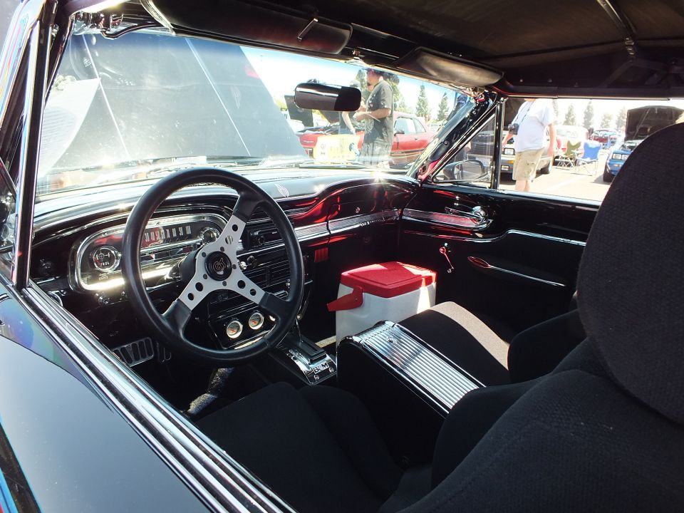 Black-trimmed interior of a custom classic car with deep-red dash and black seats